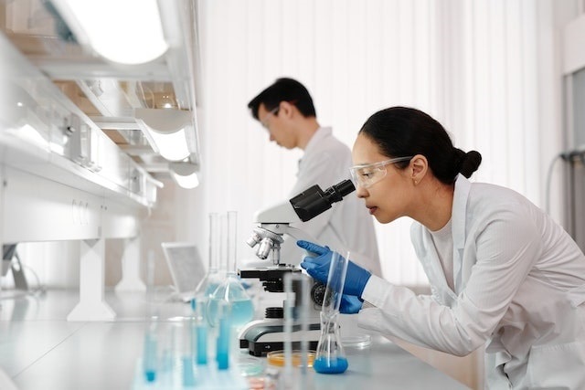 Medical researchers using microscope and other equipment in a lab