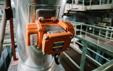 Close-up of an orange pump motor with a clearly visible metal nameplate and warning label attached